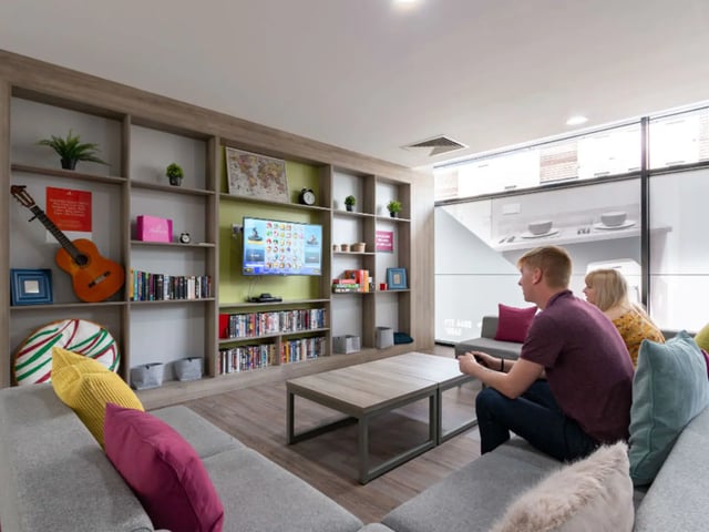 Sofa bookshelves TV with game and people living room at AXO Kingston in Kingston Upon Thames Student Accommodation