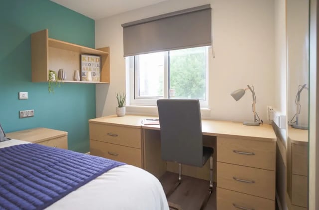 Bed with blue quilt desk chair lamp bedroom at Park View in Manchester Student Accommodation