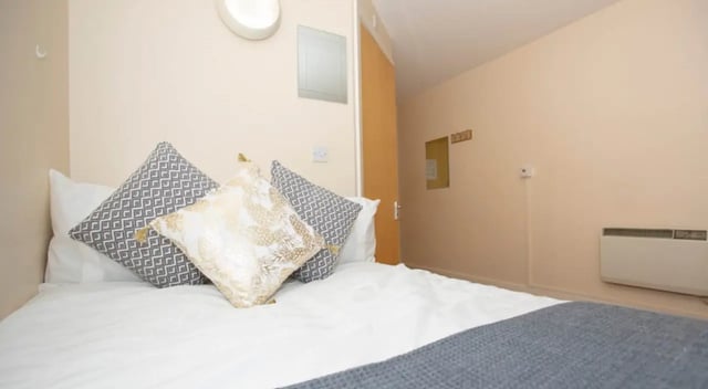 Bed with patterned pillows and grey throw bedroom at Park View in Manchester Student Accommodation