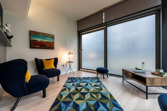 Two dark blue chairs artwork rug coffee table living room at St. Andrew Street in Aberdeen Student Accommodation