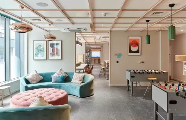 Curved sofa foosball tables modern lounge living area at Flora Building - Hoxton in London Student Accommodation