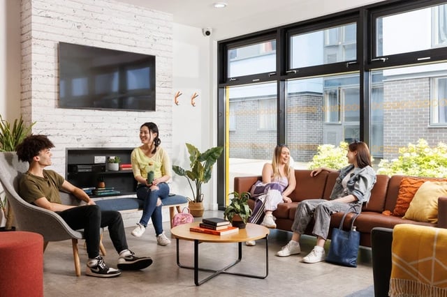 Students lounging on sofa coffee table living area at Byron Central in Newcastle Upon Tyne Student Accommodation