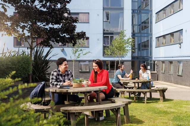 Students sitting at picnic tables exterior at Byron Central in Newcastle Upon Tyne Student Accommodation