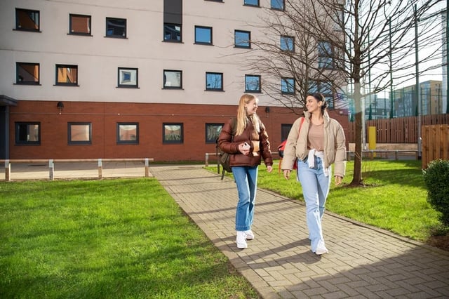 Two students walking on path exterior at James Watt in Birmingham Student Accommodation
