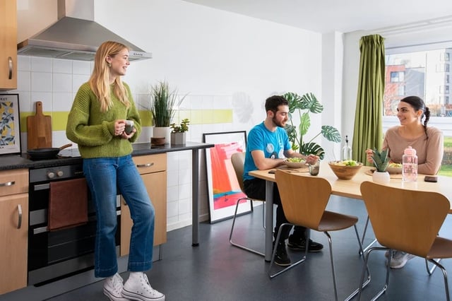 Kitchen with people dining and cooking kitchen area at James Watt in Birmingham Student Accommodation