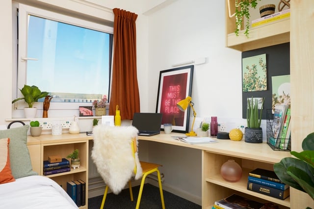 Desk with laptop lamp framed art and plants bedroom at James Watt in Birmingham Student Accommodation