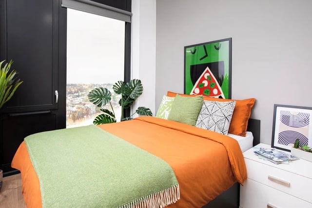 Bed with orange duvet and plants bedroom at Battery Park in Birmingham Student Accommodation
