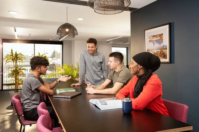Students talking at a communal table living room at Battery Park in Birmingham Student Accommodation
