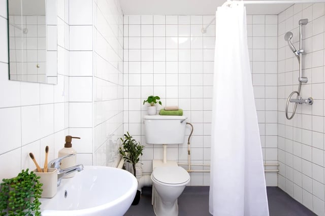 Sink toilet shower with curtain white tiled bathroom at Romano Court in London Student Accommodation