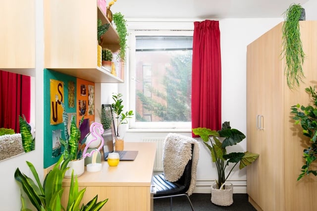 Desk with laptop plants and flamingo lamp bedroom at Romano Court in London Student Accommodation