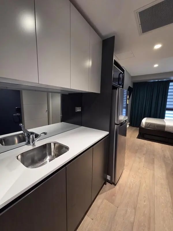 Modern kitchenette with bed in background studio at Sydney Student Living Top Ryde in Sydney Student Accommodation