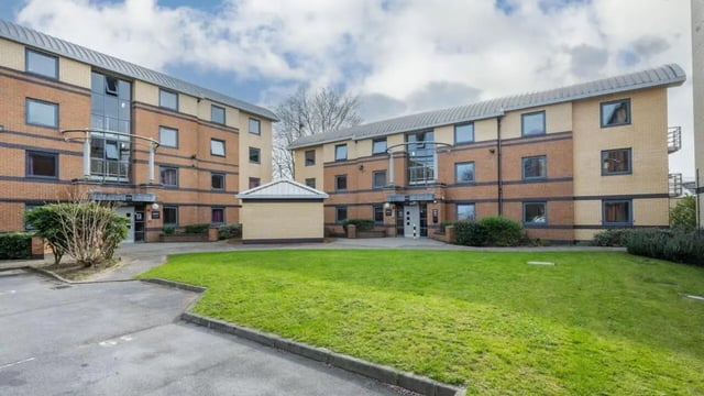 Brick apartment buildings with lawn and parking exterior at Clarence Dock Village in Leeds Student Accommodation