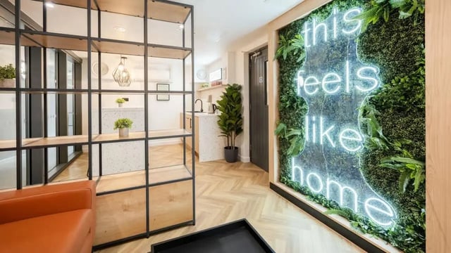 Shelving unit neon sign and plant wall lounge area at Curzon House in Nottingham Student Accommodation