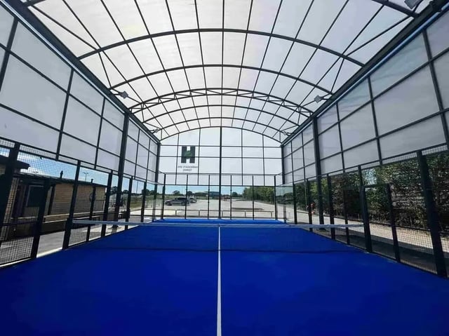 Blue padel court with glass walls and roof playing area at Foundry Courtyard in Glasgow Student Accommodation