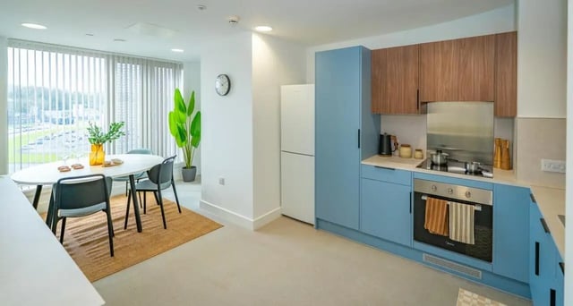 Dining table chairs modern kitchen with blue cabinets kitchen at The Propeller Quarter in Bristol Student Accommodation