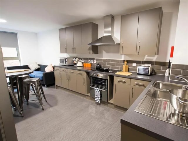 Modern kitchen with grey cabinets stove and sofa kitchen area at Foundry Courtyard in Glasgow Student Accommodation