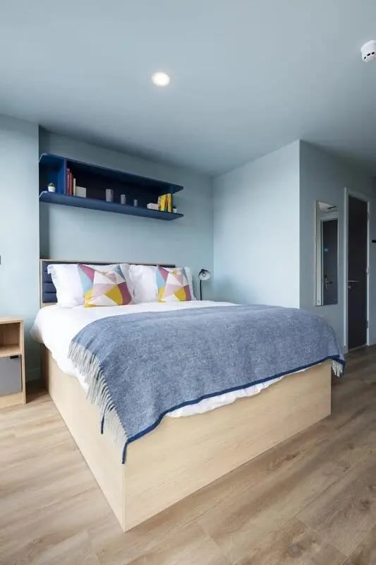 Bed with blue throw and patterned pillows Bedroom at Coleman Court in Cork Student Accommodation