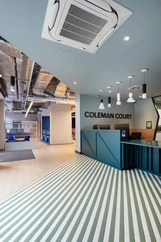 Reception desk with striped floor and seating area. at Coleman Court in Cork Student Accommodation