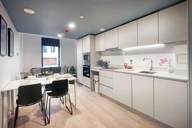 Dining table kitchen counters sink oven and sofa living room at Bradbury Place in Belfast Student Accommodation