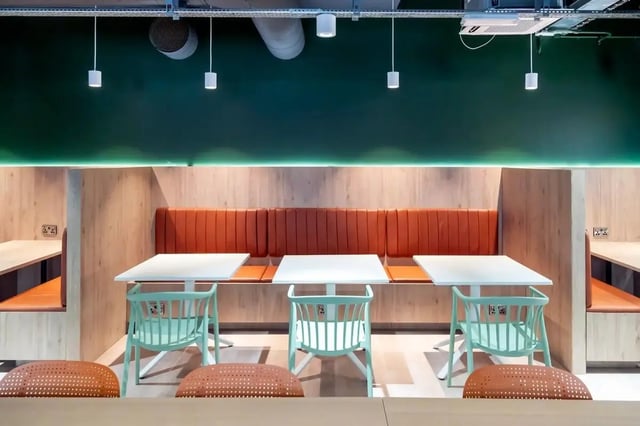 Orange booth seating with white tables and chairs communal area at Bradbury Place in Belfast Student Accommodation