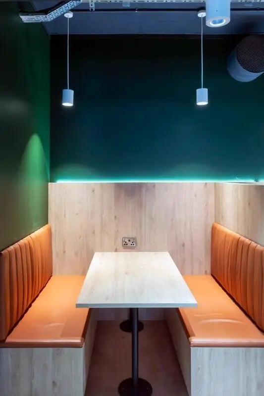 Table with orange booths and wood paneling dining area at Bradbury Place in Belfast Student Accommodation