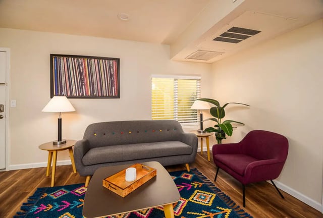 Sofa armchair rug coffee table plant artwork living room at Union on Bellevue in Tucson Student Accommodation