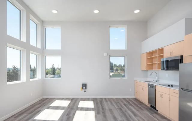 Modern kitchen with light wood cabinets dishwasher and microwave kitchen at Ace Apartments in Seattle Student Accommodation