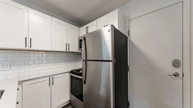 White cabinets stainless steel fridge stove and door kitchen at Victory East Lansing in East Lansing Student Accommodation