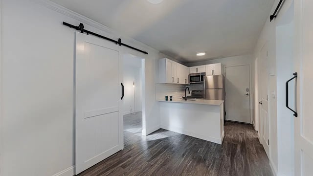 White barn door opens to modern kitchen living area at Victory East Lansing in East Lansing Student Accommodation