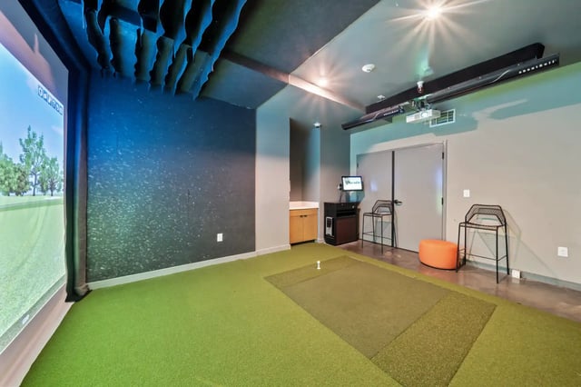 Golf simulator with screen and green turf playing area at The Villas at San Gabriel in Austin Student Accommodation