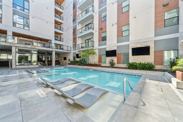 Modern apartment pool with lounge chairs and building exterior pool at The Villas at San Gabriel in Austin Student Accommodation