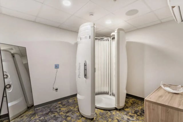 Tanning bed with mirror and cabinet tanning room at The Bridge on Forbes Apartments in Pittsburgh Student Accommodation