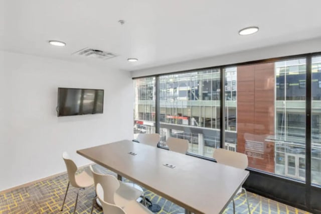 Table with chairs and wall mounted television study area at The Bridge on Forbes Apartments in Pittsburgh Student Accommodation