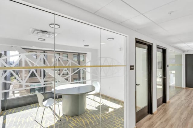 Glass room with table chairs and hallway exterior at The Bridge on Forbes Apartments in Pittsburgh Student Accommodation