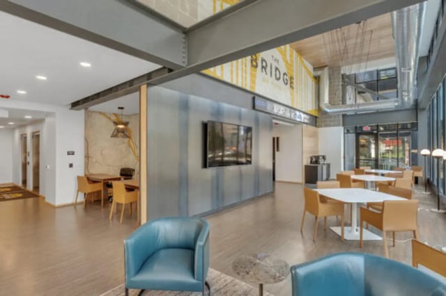 Modern lounge with tables chairs television and study areas lounge at The Bridge on Forbes Apartments in Pittsburgh Student Accommodation