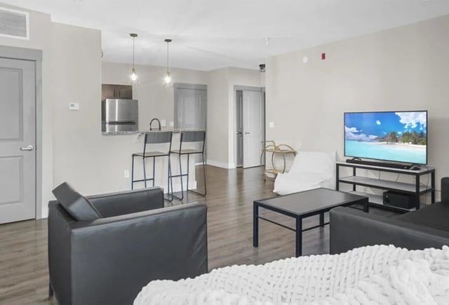Chairs kitchen island television and coffee table living room at 10 North in Bloomington Student Accommodation