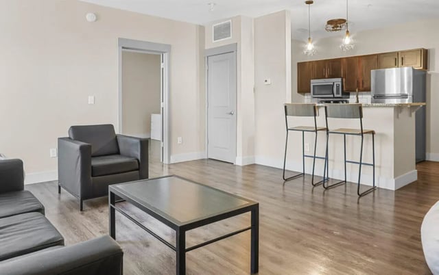 Sofa armchair coffee table kitchen area living room at 10 North in Bloomington Student Accommodation