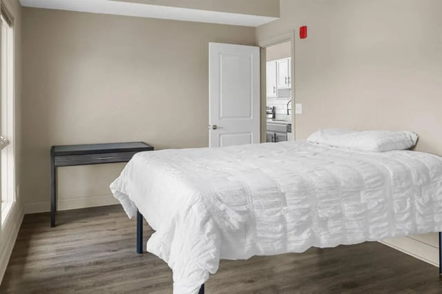 Bed and desk visible through open doorway kitchen bedroom at 10 North in Bloomington Student Accommodation