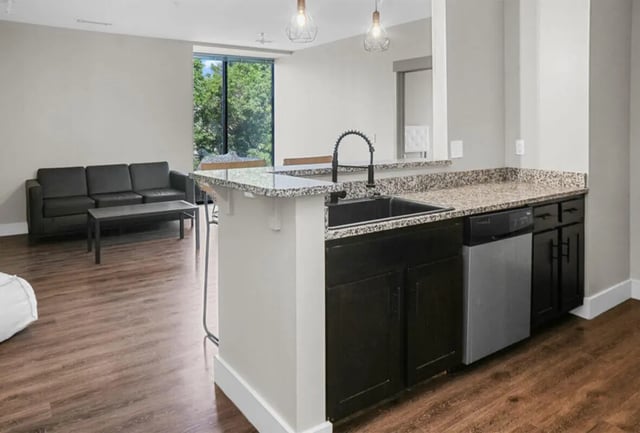 Black couch coffee table kitchen island Living area at 10 North in Bloomington Student Accommodation
