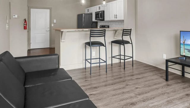 Living room with sofa kitchen island bar stools and television Living room at 10 North in Bloomington Student Accommodation