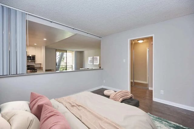 Bed with pink pillows kitchen visible bedroom at Ariel Court in Los Angeles Student Accommodation