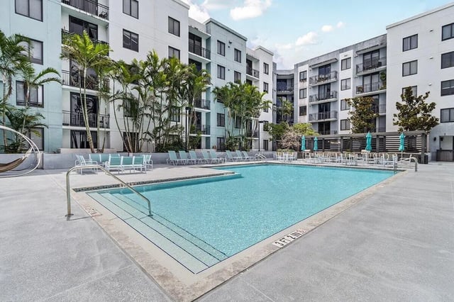 Pool lounge chairs tables umbrellas exterior at 4th Street Commons Apartments in Miami Student Accommodation