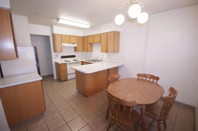 Kitchen with wooden cabinets dining table and chairs kitchen at Afton Apartments in Logan Student Accommodation