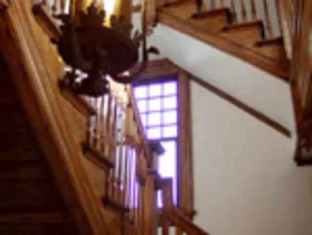 Wooden staircase with window and chandelier interior area at Ashley Management Corporation in Ithaca Student Accommodation