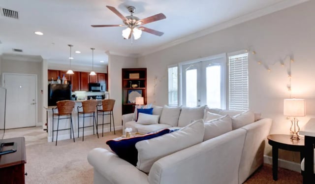White sofas ceiling fan kitchen bar stools living room at Ashton Lane Luxury Apartments in Gainesville Student Accommodation