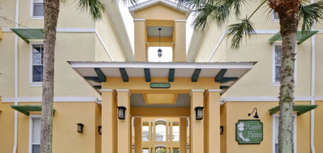Yellow building entrance palm trees Royale Palms exterior at Ashton Lane Luxury Apartments in Gainesville Student Accommodation