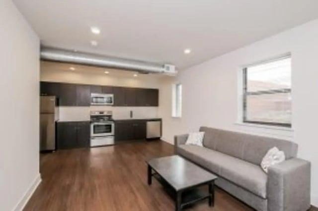 Sofa coffee table kitchen appliances dark cabinets living area at Cooper Village in Camden Student Accommodation