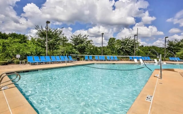 Blue lounge chairs surround a sparkling swimming pool exterior at The Flats At Carrs Hill in Athens Student Accommodation