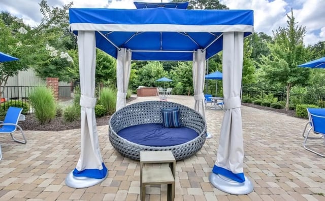 Round seating cabana with blue cushions and tables outdoors living area at The Flats At Carrs Hill in Athens Student Accommodation