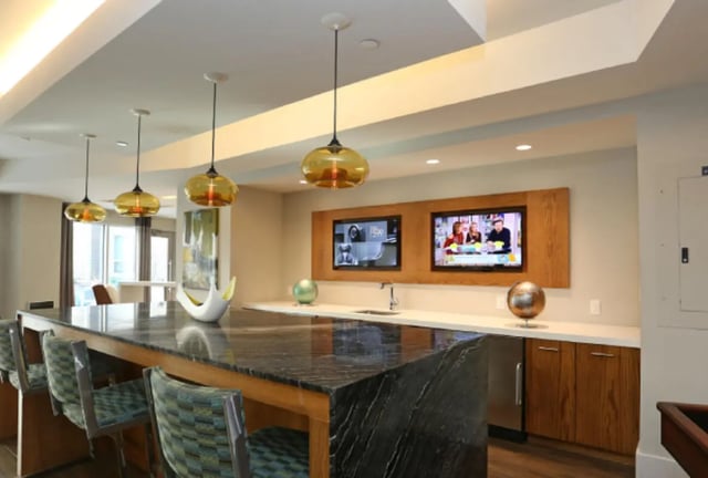 Bar with stools, sink, and TVs, lounge area at College and Crown Apartments in New Haven Student Accommodation